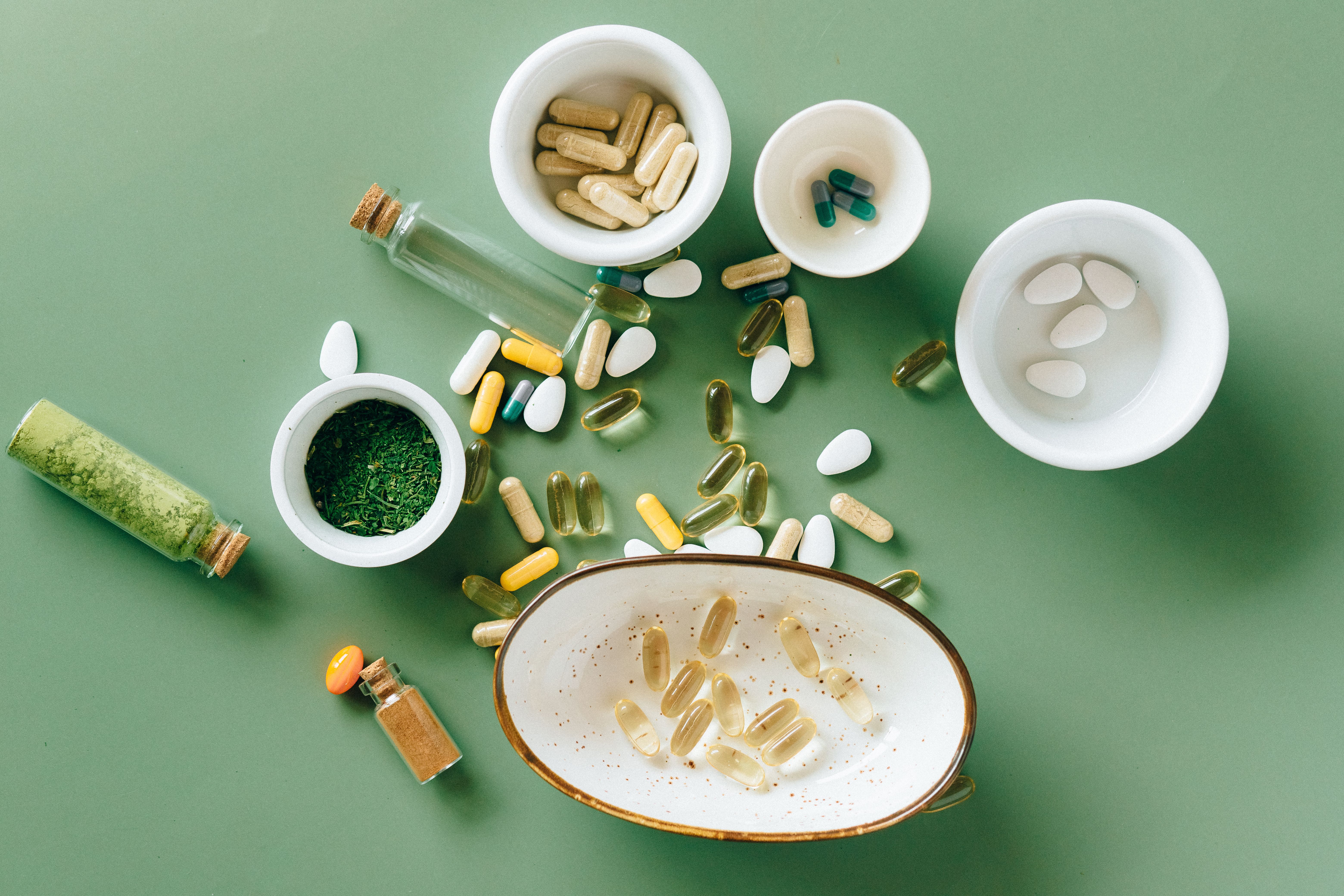 Assorted vitamins, capsules, and supplements arranged in small bowls
